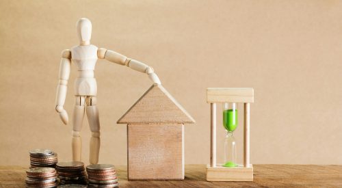 Wooden mannequin with house model, coins, and hourglass symbolizing financial planning.